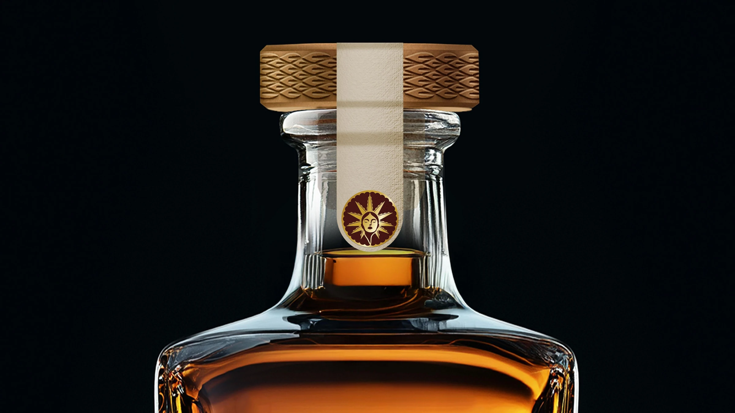 Cuello de la botella del Reposado: tapón dorado con relieve tejido, cinta de papel y emblema guinda y oro con un rostro al centro de un sol